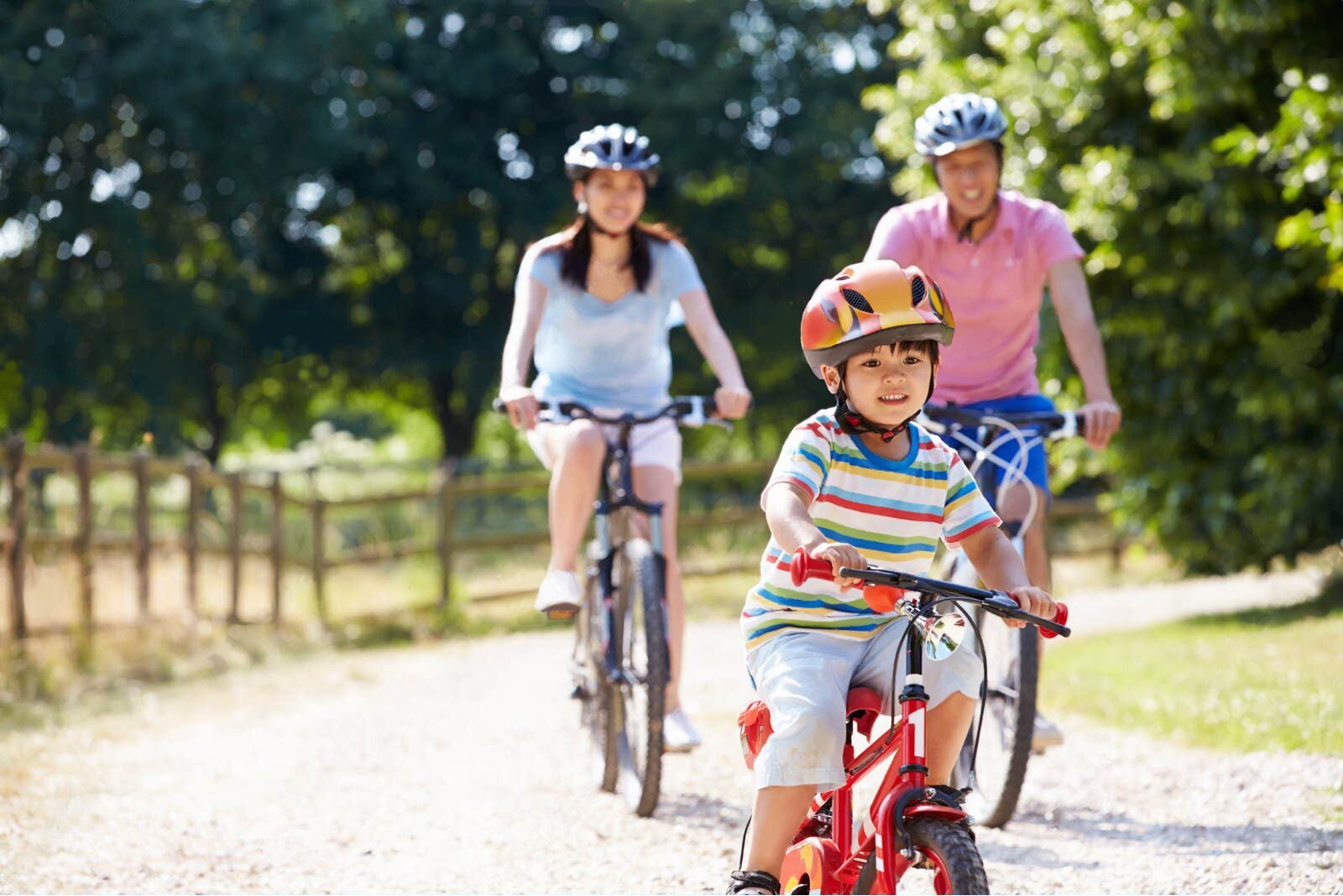 Kind in voorgrond en twee ouders fietsen op een fietspad